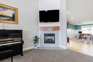 Living area featuring recessed lighting, a tiled fireplace, wood finished floors, and wainscoting