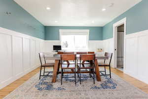 Dining room featuring a wainscoted wall, wood finished floors, and a decorative wall