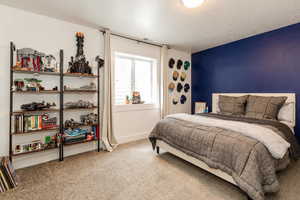 Bedroom with baseboards, visible vents, carpet floors, and a textured ceiling