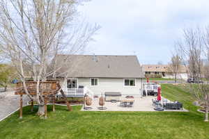 Rear view of house featuring a shingled roof, an outdoor hangout area, a yard, a wooden deck, and a patio area