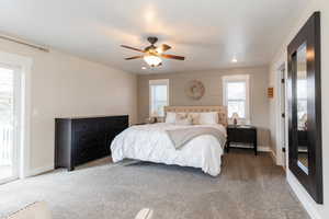 Carpeted bedroom with access to exterior, a ceiling fan, and baseboards