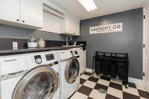 Clothes washing area with cabinet space, washing machine and clothes dryer, and light floors