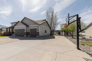 View of side of home featuring stone siding, driveway, and a garage