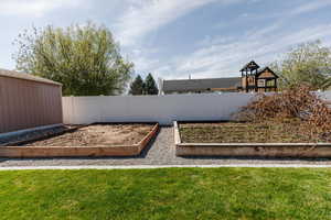 View of yard featuring fence and a vegetable garden