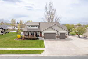 Craftsman inspired home with concrete driveway, stone siding, a shingled roof, an attached garage, and a front yard