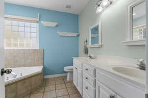 Full bath with visible vents, toilet, a sink, a bath, and baseboards