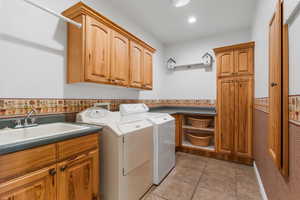 Clothes washing area featuring washer and clothes dryer, a sink, light tile patterned floors, cabinet space, and recessed lighting