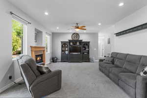 Carpeted living area featuring a fireplace, baseboards, recessed lighting, and a ceiling fan