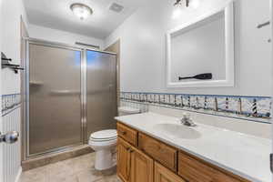 Bathroom featuring toilet, tile patterned flooring, visible vents, and a stall shower