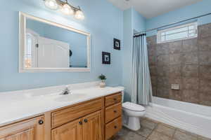 Bathroom with shower / tub combo with curtain, vanity, tile patterned floors, and toilet