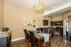 Dining room with a chandelier, baseboards, dark wood-type flooring, visible vents, and recessed lighting