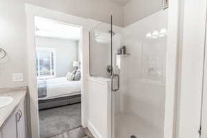 Ensuite bathroom featuring vanity, ensuite bathroom, wood finished floors, and a shower stall
