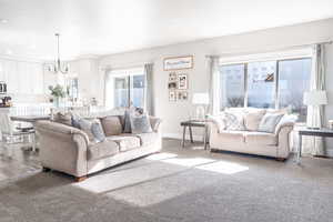 Carpeted living area with baseboards, recessed lighting, and a chandelier