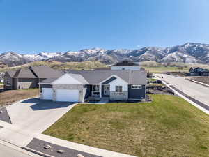 View of front of property featuring driveway, a front yard, a mountain view, and a garage
