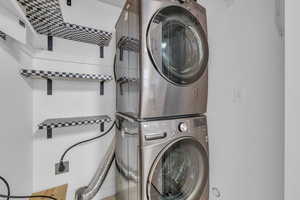 Laundry room with stacked washer and dryer and shelving