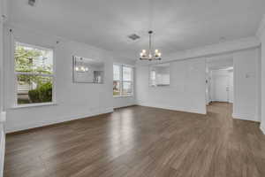 Unfurnished living room with a chandelier, laminate floors, fireplace, and stairway
