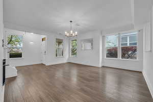 Unfurnished living room with a chandelier, laminate floors, fireplace, and stairway