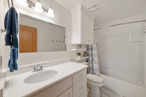 Bathroom with marble finish floor, visible vents, toilet, vanity, and shower / tub combo with curtain