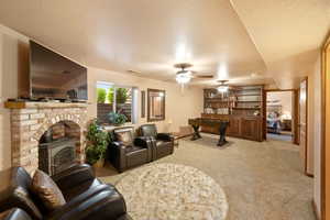 Living area featuring ceiling fan, light carpet, a textured ceiling, and visible vents