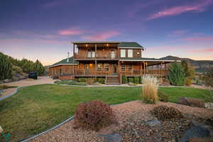 Back of property featuring a balcony and a yard