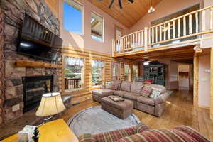Living room featuring a stone fireplace, a high ceiling, and ceiling fan