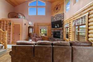 Living room featuring high vaulted ceiling, wood finished floors, a wealth of natural light, a fireplace, and stairs