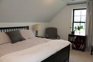 Bedroom with lofted ceiling and light carpet