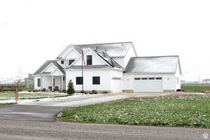Modern farmhouse with an attached garage, a front yard, fence, and driveway