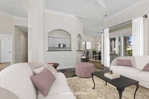 Living room with stone finish floor, baseboards, arched walkways, ornamental molding, and a ceiling fan