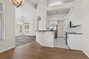 Kitchen with dark countertops, white cabinetry, a kitchen breakfast bar, and stainless steel appliances