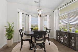 Dining room with visible vents, a chandelier, baseboards, vaulted ceiling, and wood finished floors
