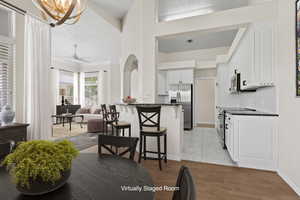 Kitchen with a kitchen breakfast bar, white cabinetry, appliances with stainless steel finishes, dark countertops, and baseboards