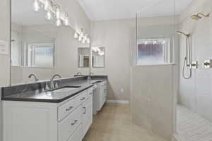 Bathroom featuring double vanity, tile patterned flooring, a walk in shower, and a sink