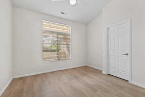 Empty room featuring light wood-type flooring, baseboards, a ceiling fan, and visible vents