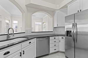 Kitchen featuring a wealth of natural light, ornamental molding, stainless steel appliances, and a sink