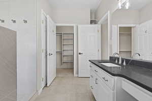Full bathroom with vanity, tile patterned flooring, a shower, and a walk in closet