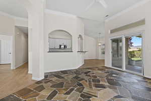 Interior space featuring a high ceiling, arched walkways, stone floors, and crown molding
