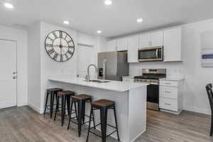 Kitchen featuring a sink, stainless steel appliances, a kitchen bar, baseboards, and visible vents
