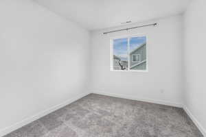 Spare room featuring carpet floors, visible vents, and baseboards
