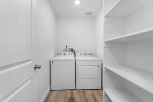 Clothes washing area with light wood finished floors, washer and dryer, and laundry area
