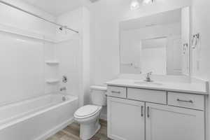Bathroom featuring wood finished floors, vanity,  shower combination, toilet, and visible vents