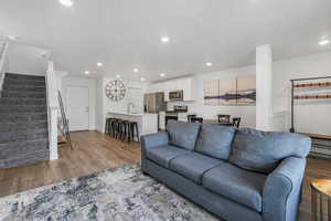 Living room with stairway, recessed lighting, and light wood-type flooring