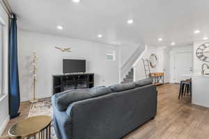 Living area with stairway, baseboards, wood finished floors, and recessed lighting