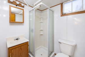 Full bath featuring vanity, a shower stall, and toilet