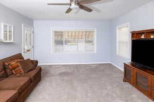 Living room featuring baseboards, carpet, and ceiling fan