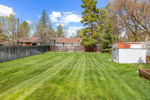 View of yard featuring fence, an outbuilding, and a shed
