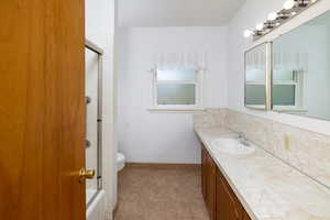 Full bathroom with tasteful backsplash, toilet, baseboards, tile patterned flooring, and vanity