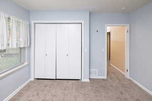 Unfurnished bedroom featuring baseboards, a closet, visible vents, and carpet