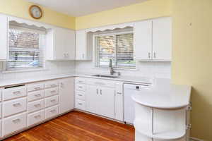 Kitchen featuring white cabinets, light countertops, a sink, tasteful backsplash, and dishwasher