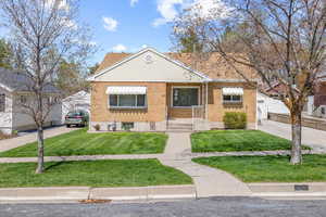 Bungalow-style house featuring a front lawn, brick siding, and driveway